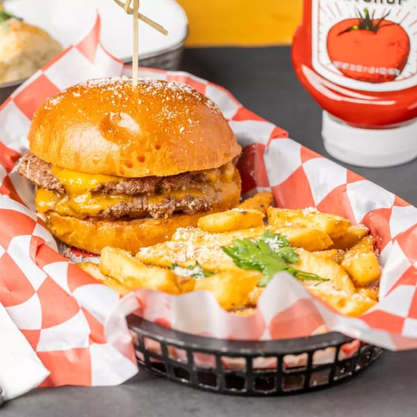Double cheeseburger with fries in a basket, ketchup bottle in background at Vito's.