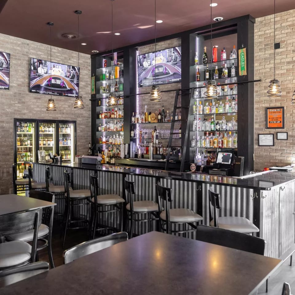 Vito's Coal Fired Pizza & Restaurant bar area with brick walls, liquor shelves, and TVs.