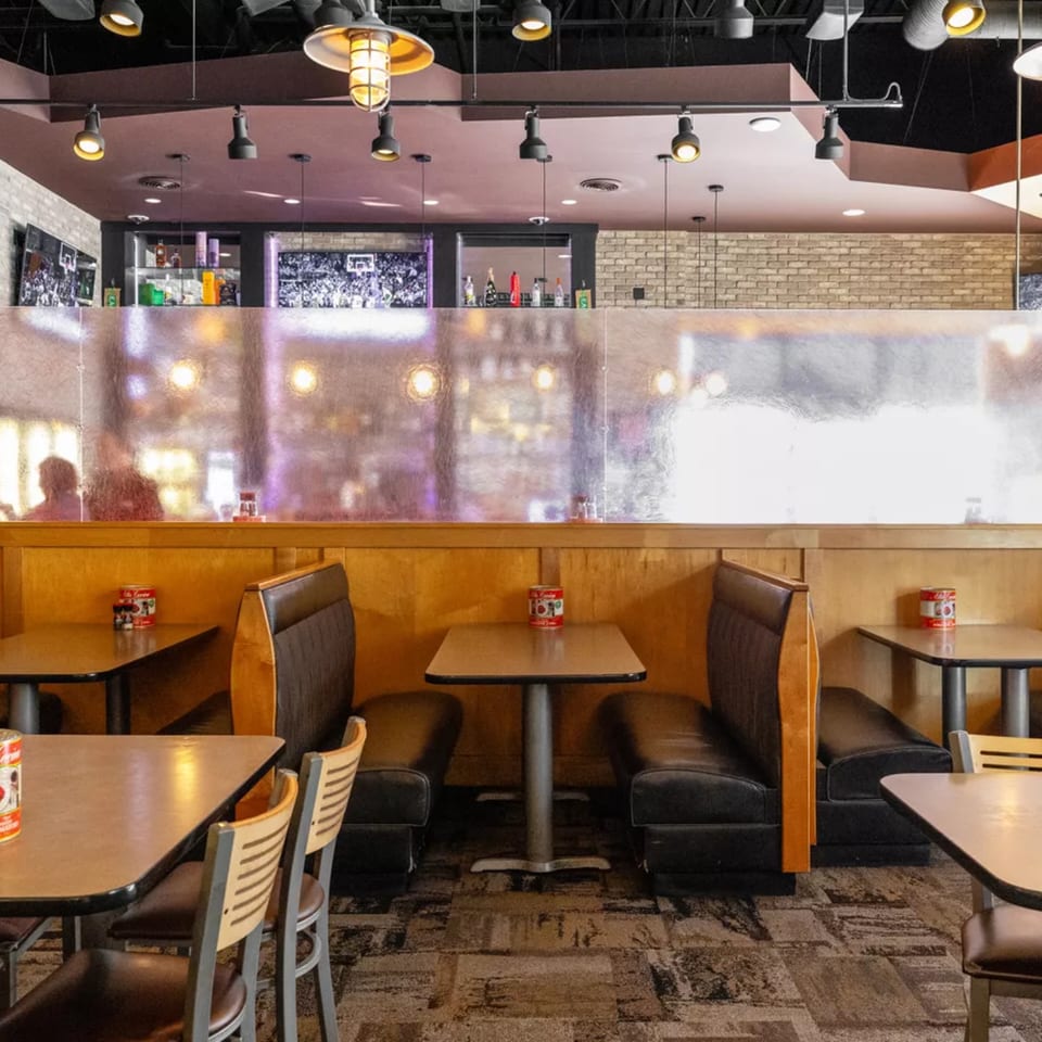 Interior of Vito's Coal Fired Pizza & Restaurant with booths, tables, and a bar area.